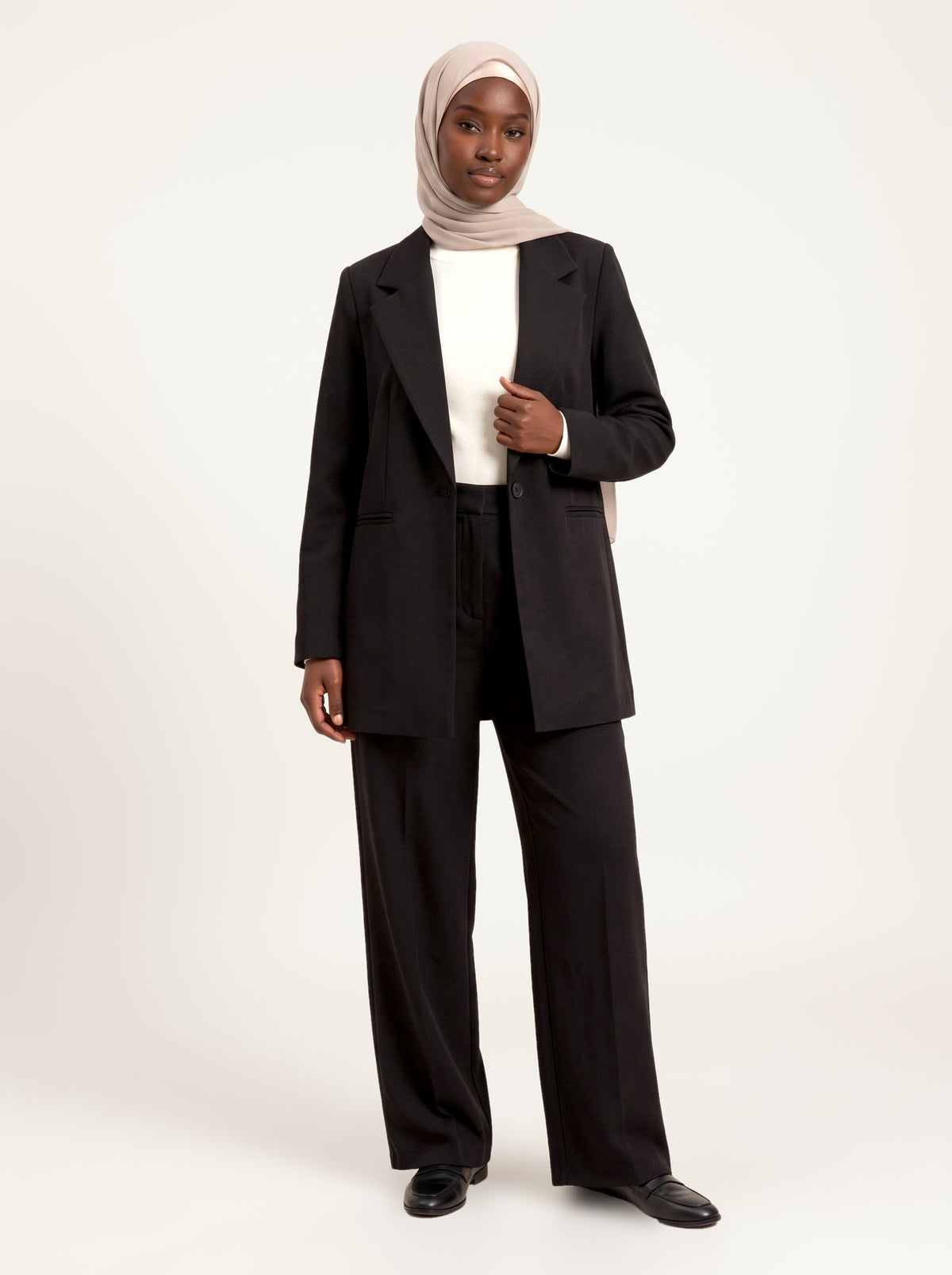 Ensemble tailleur blazer long et pantalon large noir, porté