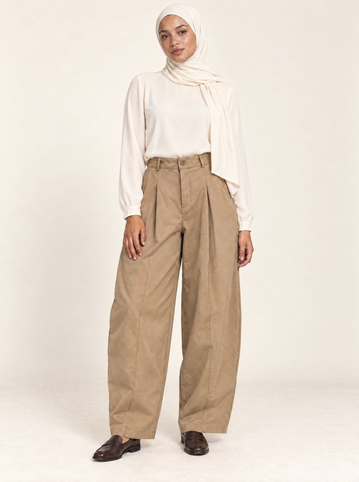 Pantalon large à pinces beige porté avec une blouse crème