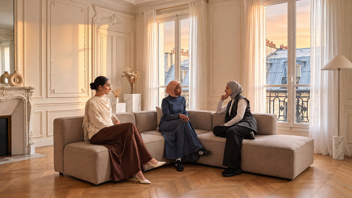 Trois femmes assises sur un canapé dans un salon haussmannien baigné de lumière dorée