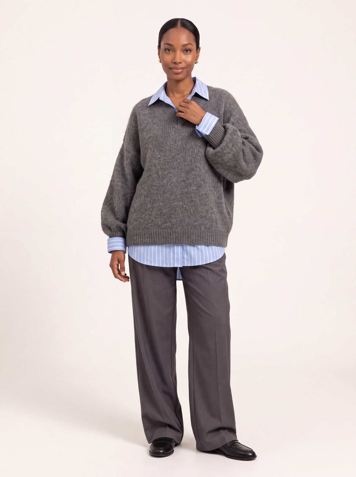Pull col V oversize gris chiné porté de face avec une chemise rayée