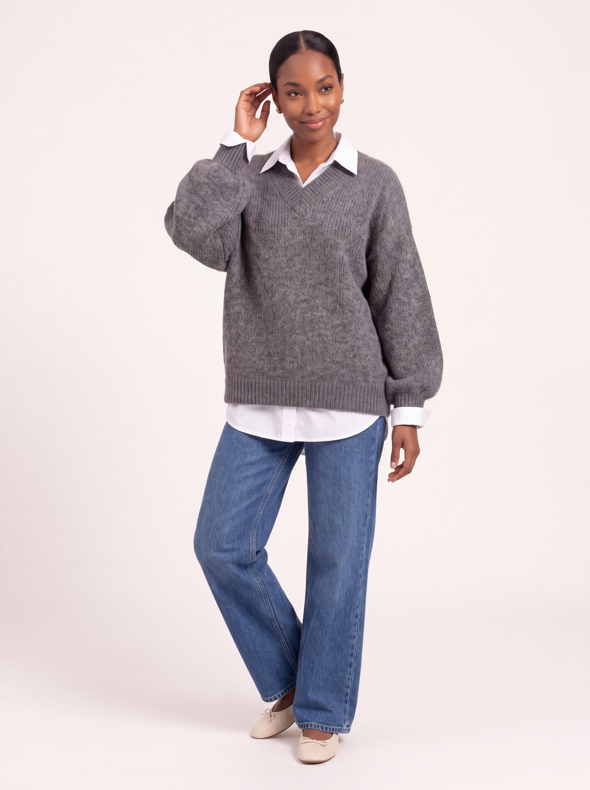Pull col V oversize gris chiné porté avec une chemise blanche et un jean